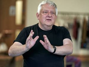 Photo of Simon Russell Beale wearing a black top. He's gesturing with both of his hands in front of him as if explaining something.