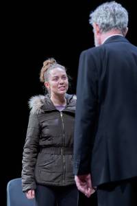 Sarah Twomey stands opposite Alex Jennings, she wears a puffer jacket.