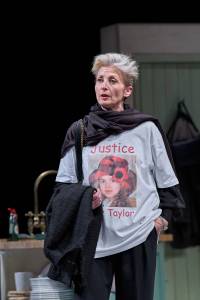 Hermione Gulliford stands, she is in conversation and wears a large white t shirt with a photo of young girl on it, it reads 'Justice for Taylor'.