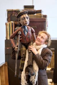 Lyndsey Marshal smiles as she holds a large wooden puppet of a young boy..