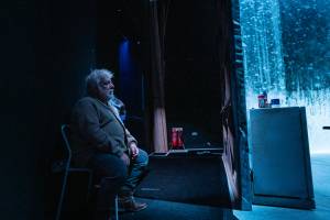 Simon Russell Beale sits waiting to go onstage, the set can be seen.