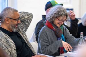 Two people laugh sat at a table.