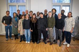 The cast of Richard II stand in a large group smiling.