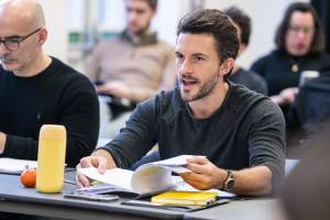 Jonathan Bailey sits at a table with a script in hand.