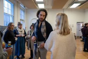 Two people in friendly conversation in a large room with high ceilings.