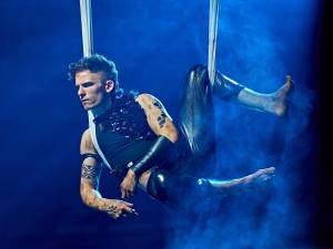 Puck sits, in aerial silks